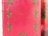 an old book with a red cover and a gold border