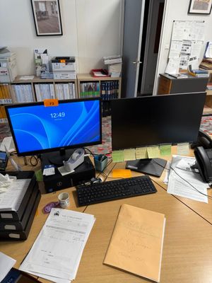 un bureau sur lequel se trouvent un ordinateur, une imprimante, un téléphone et d'autres objets