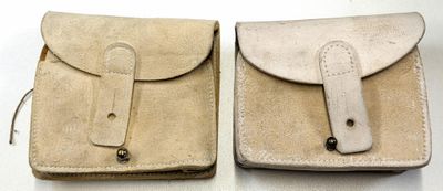 une paire de pochettes en cuir beige avec une poignée en bois, posées sur une surface blanche