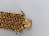 a close up of a gold bracelet on a white surface