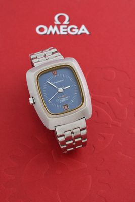 une image représentant une montre en argent posée sur un coffret rouge orné d'un logo