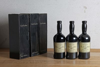 trois bouteilles de vin posées sur une table, à côté d'une boîte de livres