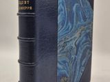 un vieux livre à la couverture bleue posé sur une table blanche