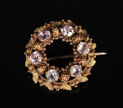 un gros plan sur une broche en or sertie de pierres roses