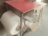 une table rouge sur laquelle est posé un rouleau de papier toilette