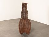 a tall wicker chair in the corner of a room