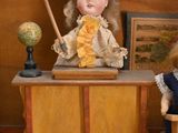 two dolls that are sitting on a desk in a doll house