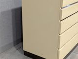 beige metal filing cabinet with five drawers in a room