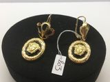 deux paires de boucles d'oreilles en or sur un chapeau noir muni d'une étiquette de prix