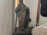 a statue of jesus sitting on a table next to a candle