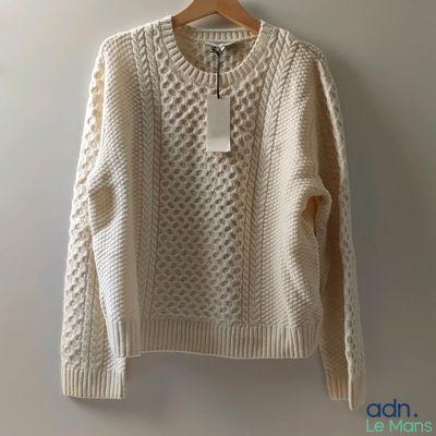 a white sweater hanging on a hanger against a wall