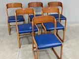 six chairs with blue leather seats in a room with a wall in the background