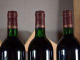three bottles of wine are lined up on a shelf