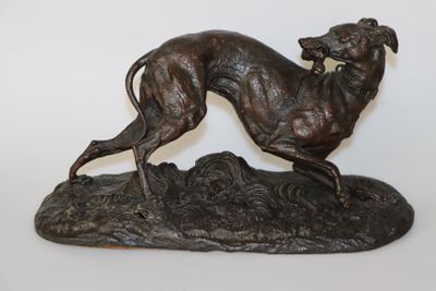 statue en bronze représentant un lévrier posé sur un rocher, sur fond blanc