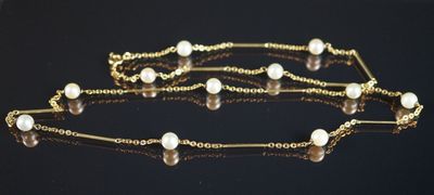 chaîne en or ornée de perles, posée sur un fond noir