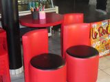 three red stools and a table in the middle of a restaurant