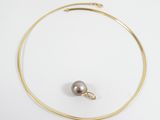 a close up of a gold necklace with a pearl on it