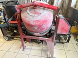 une bétonnière rouge posée par terre dans un garage