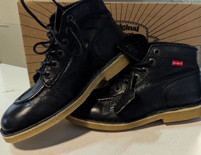 une paire de bottes en cuir noir posée sur une table blanche
