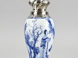 a blue and white vase with a silver lid sitting on a table