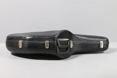 an old black guitar case sitting on top of a white table