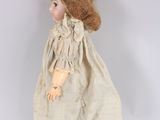 an old fashioned doll with red hair and a white dress