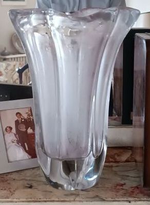 un vase en verre posé sur une table, à côté d'un tableau