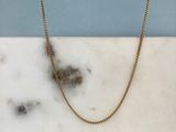 gold plated chain on a marble slab with a blue wall in the background