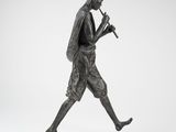 une statue en bronze représentant un homme marchant, une flûte à la main