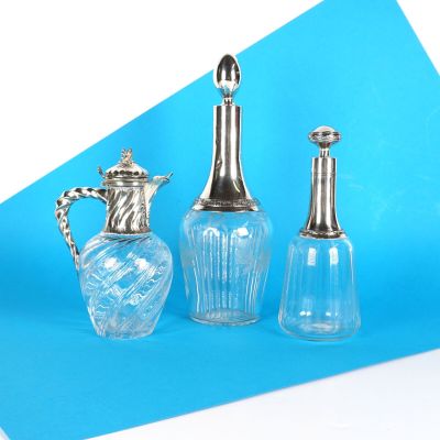 trois vases en verre et un vase en argent sur fond bleu