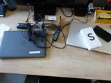 a desk with a laptop, phone, and other electronics on it