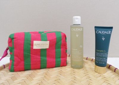 un sac rose et vert posé sur une table à côté d'un flacon de lotion