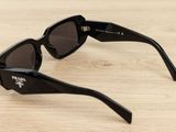 sunglasses on a wooden table with a black frame and brown lens