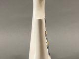 a white vase with a wooden top on a gray surface