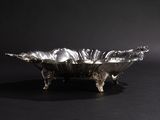 an antique silver plate with a decorative design on a black background