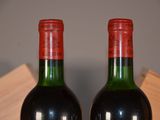 two bottles of red wine sitting on top of a wooden table