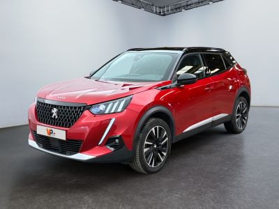 La voiture rouge est garée dans une grande pièce au sol noir.