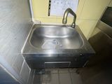 un évier en acier inoxydable dans le coin d'une toilette publique