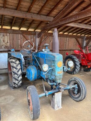 un tracteur bleu garé dans une grange avec d'autres tracteurs