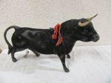 figurine représentant un taureau noir avec un ruban rouge autour du cou