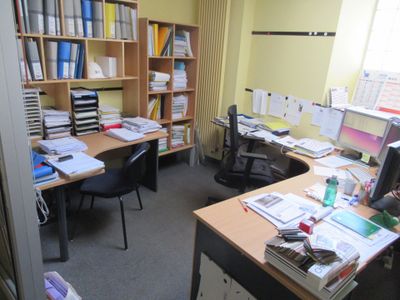 une pièce équipée d'un bureau, d'une chaise, d'une bibliothèque et d'un écran d'ordinateur