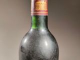 an old bottle of wine sitting on top of a wooden table