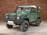 a picture of a green land rover parked in front of a brick wall