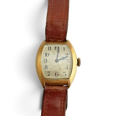 une petite montre-bracelet en or avec un bracelet en cuir marron