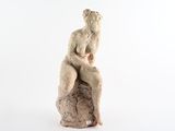 statue d'une femme assise sur un rocher, sur fond blanc