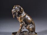 une statue en bronze représentant un chien assis sur une table