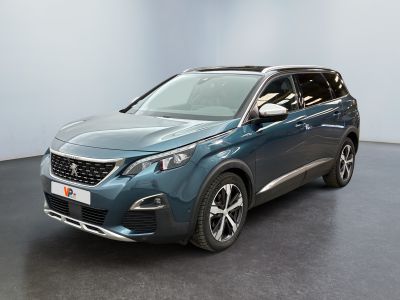 La voiture bleue est garée dans une grande pièce au sol noir.