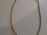 gros plan d'un collier en or sur une surface blanche