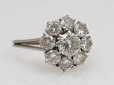 a close up of a diamond cluster ring on a white surface
