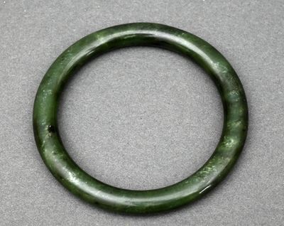 un gros plan d'un bracelet vert posé sur une surface grise